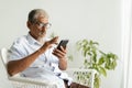 Pleasant senior older men resting while sitting on chair, Asian elder man with grey hair using application on smartphone at home Royalty Free Stock Photo