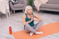 Pleasant senior woman meditating at living room