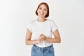 Pleasant smiling girl looking friendly, holding hands together, consultant ready to help, standing on white background Royalty Free Stock Photo
