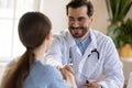 Pleasant smiling male doctor meeting young woman patient at clinic