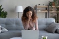 Pleasant smiling young woman in glasses looking at laptop screen