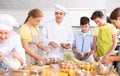 Sociable young chef leading culinary courses to group of tweens