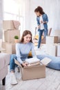 Pleasant student unpacking books while her roommate cleaning flat Royalty Free Stock Photo