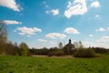 Pleasant sunny summer landscape: old blue sky and clouds, green grass and old historical Slavic Orthodox country church building Royalty Free Stock Photo