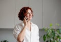 Pleasant talk with friend. Attractive smiling young redhead woman talking on cell phone . Technology, communication and coziness Royalty Free Stock Photo