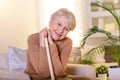 Pleasant thoughtful aged woman seating with a walking stick. Retired woman with her wooden walking stick at home. Happy senior Royalty Free Stock Photo