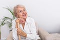 Pleasant thoughtful aged woman seating with a walking stick. Retired woman with her wooden walking stick at home. Happy senior Royalty Free Stock Photo