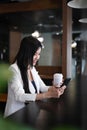 Pleasant woman entrepreneur sitting in office shop and using smartphone.