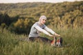 Pleasant woman in hijab and sport clothes sitting on yoga mat and stretching body. Royalty Free Stock Photo