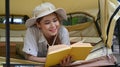 Pleasant woman traveler reading book while lying inside camp tent. Travel, adventure and vacation concept Royalty Free Stock Photo