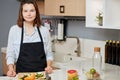 Pleasant young chef is standing at the table and going to cook something tasty