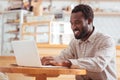 Pleasant young man working on laptop in coffeehouse