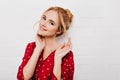 Pleasant young woman in red shirt playing with blonde hair. Close-up indoor portrait of charming blue-eyed european girl Royalty Free Stock Photo