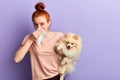 Pleasant young woman in sylish casual clothes closing her nose with paper towel