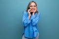 pleasantly surprised cute blonde woman chatting on the phone on a blue bright background Royalty Free Stock Photo
