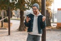 Pleasantly surprised. With smartphone. Beautiful man in warm clothes is outdoors in the park