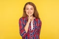 Please, be quiet! Portrait of cheerful ginger girl holding finger on lips making hush silence gesture and smiling Royalty Free Stock Photo