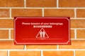 Please beware of your belongings sign on red brick wall Royalty Free Stock Photo