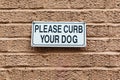 Please Curb Your Dog sign on a brick wall