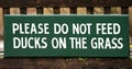 Please Do Not Feed Ducks On The Grass - wooden sign on bench background or banner image Royalty Free Stock Photo