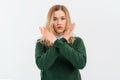 Please, do not, stop. Young serious woman with fair-haired in casual clothes, crossing arms and palms doing negative sign,