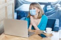 Please help. Portrait of worry young woman with surgical medical mask is sitting and working on laptop and looking display and Royalty Free Stock Photo