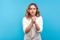 Please, I`m begging! Portrait of pleading woman holding hands in prayer, asking permission. isolated on blue background Royalty Free Stock Photo