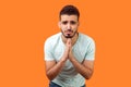 Please, I`m begging! Portrait of upset brunette man holding arms in prayer, asking help. indoor studio shot isolated on orange