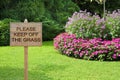 Please Keep Off The Grass - concept with wooden pole on a green meadow with sign indicating Royalty Free Stock Photo