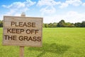 Please Keep Off The Grass - concept with wooden pole on a green meadow with sign indicating Royalty Free Stock Photo