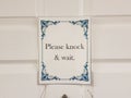 Please knock and wait sign on white door Royalty Free Stock Photo