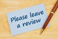 Please leave a review message on blue paper index card with pen Royalty Free Stock Photo