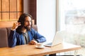 Please little bit! Portrait of cunning young adult man freelancer in casual style sitting in cafe with laptop, looking at camera, Royalty Free Stock Photo