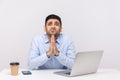 Please, need help! Upset man employee sitting office workplace with laptop on desk, holding prayer gesture