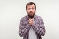 Please! Portrait of humble bearded young man holding hands in prayer, looking with imploring eyes. white background