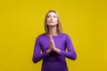 Please! Portrait of young woman holding hands in prayer and pleading. isolated on yellow background