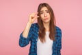 Please, some more. Portrait of cute girl in checkered shirt showing small size or little bit gesture