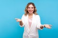 Please take! Portrait of kind cheerful woman raised hands as if sharing, giving for free. studio shot, blue background