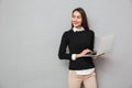 Pleased asian woman in business clothes holding laptop computer Royalty Free Stock Photo