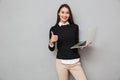 Pleased asian woman in business clothes holding laptop computer Royalty Free Stock Photo