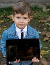 Pleased attractive child, showing digital tablet and smiling with satisfaction and positive attitude.