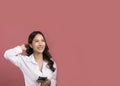 Pleased attractive young asian woman in white shirt listening music in wireless earphones touching earbuds smiling and holding Royalty Free Stock Photo