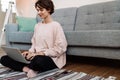 Pleased beautiful girl working with laptop while sitting on floor Royalty Free Stock Photo