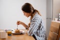 Pleased beautiful woman eating pancakes while having breakfast Royalty Free Stock Photo