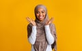 Pleased black muslim girl in hijab raising hands in happy excitement
