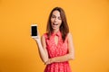 Pleased brunette woman in dress showing blank smartphone screen