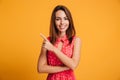 Pleased brunette woman in dress winks and pointing up