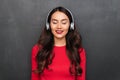 Pleased brunette woman in red blouse and headphones listening music