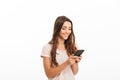 Pleased brunette woman in t-shirt writing message on smartphone