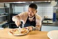 Contented cook using a roller blade knife to cut pizza Royalty Free Stock Photo